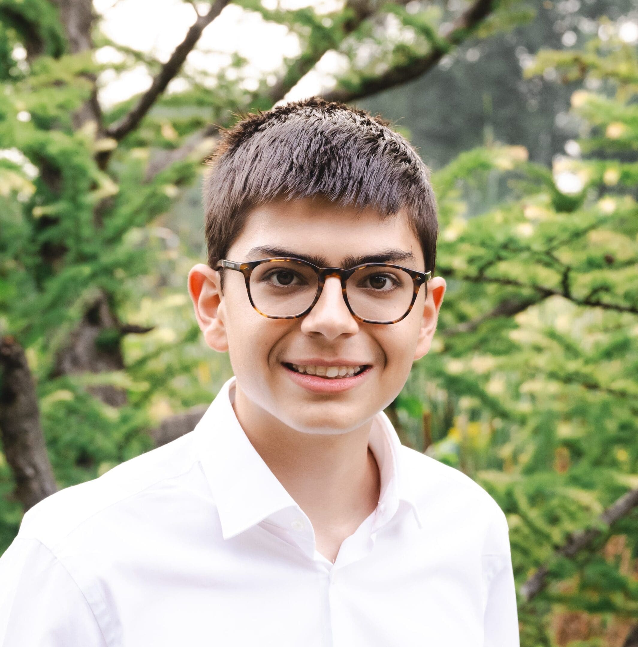 Smiling boy wearing glasses and white shirt.