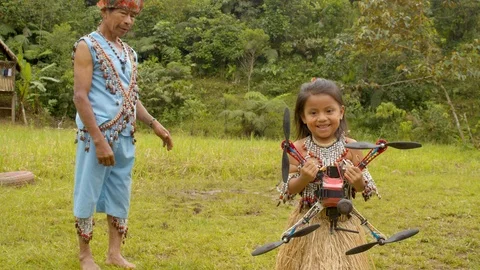 Indigenous girl holding a drone outdoors.