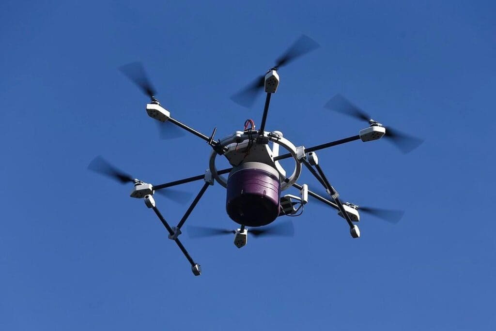 A purple and white drone flying in the sky.