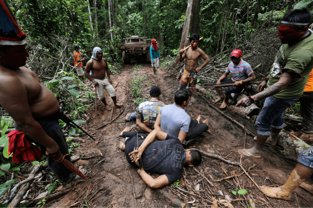 A group of people on the ground in the woods.