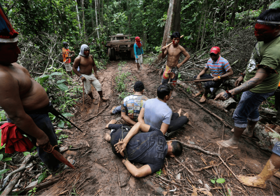 A group of people on the ground in the woods.